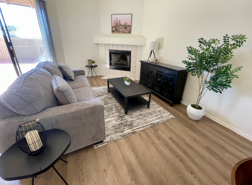 The living space of a fully furnished apartment in Tucson. featuring a sofa, coffee table, and credenza